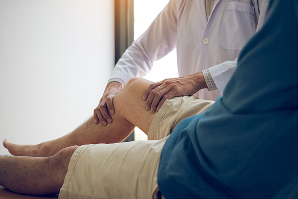doctor feeling patient's knee for treatment